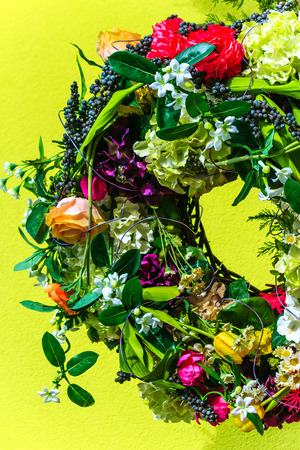Wreath of colorful flowers on yellow background の写真素材
