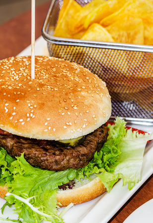 Tasty burger with homemade chips in small net basketの写真素材