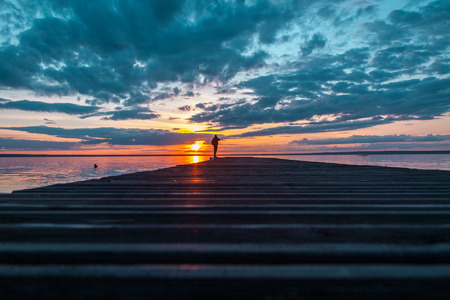 photographer takes a sunset from the bridge overlooking the big lakeの写真素材