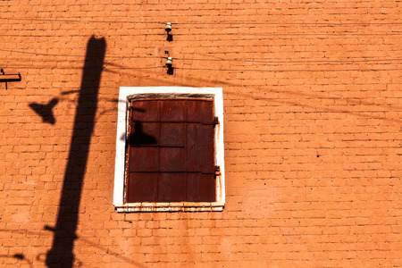 orange wall with shadows from a column and old electric lampsの写真素材