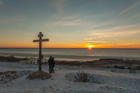 Pereslavl-Zalessky, Russia - November 28, 2015: Christian cross on Alexandrova a grief. Young people look at winter dawn over the lake.のeditorial素材