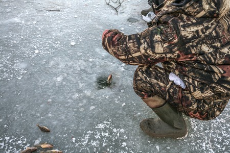 the fisherman from a hole in ice pulls out the got small fish