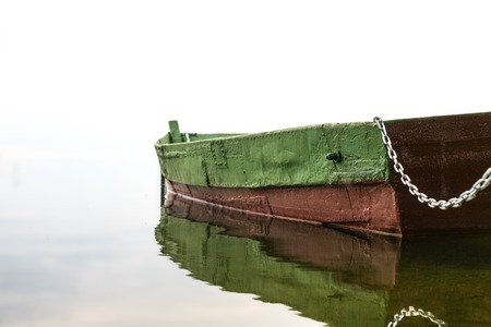 Minimalistic landscape - the old wooden boat in fog with reflection.の写真素材