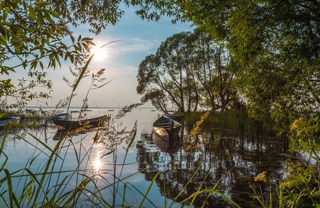 Quiet sleepy landscape with fishing boats in a silent bay in the summer evening.の写真素材