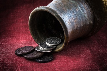 old coins dropped out on a red cloth of the fallen jugの写真素材