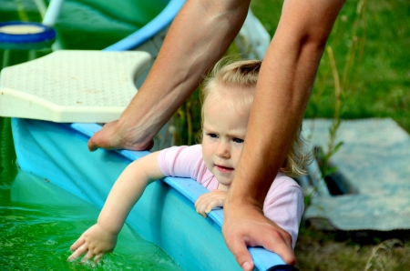 Little Baby girl with a toy. Little girl playing at the pool under the watchful eye of the Pope.の写真素材