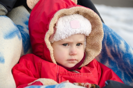 The little girl on a walk in the stroller in the winterの写真素材