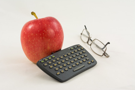 Red apple with a mini keyboard and glasses on a white background  Fun business still life 