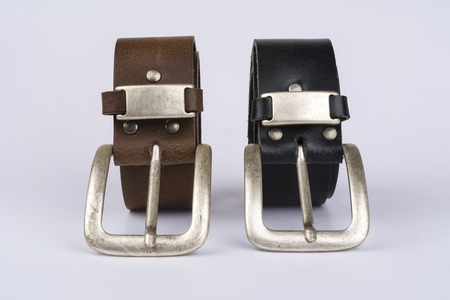Two men's leather belt, black and brown on a table on a white backgroundの写真素材