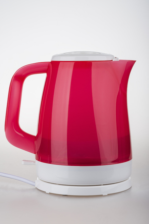 Red and White electric kettle on a stand with a round wireの写真素材