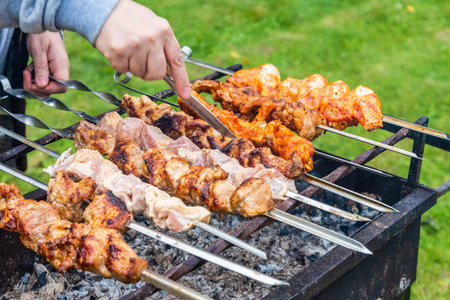 Barbecue on the grill, a hand with a knife checking the readiness of the meatの写真素材