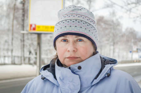 Woman in blue ski tracksuit and sports cap, next to the highway, in winterの写真素材