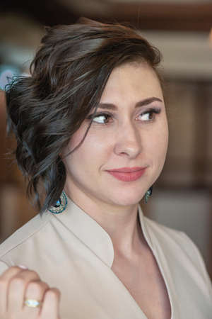 Portrait, young brunette woman, in a beige dress with a stylish hairstyleの写真素材