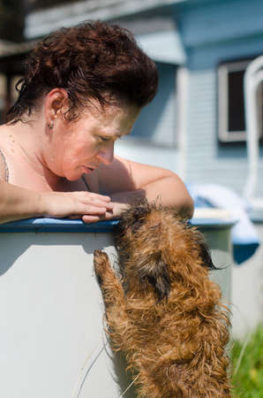 Female. on the edge of the pool, communicating with a dog - Brussels Griffinの写真素材
