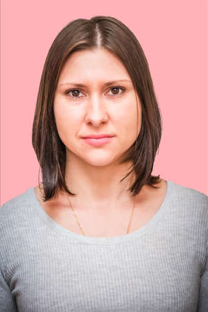 Portrait of a woman in a gray t-shirt on a pink backgroundの写真素材