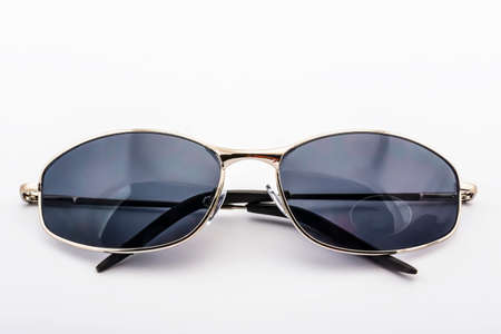Gray sunglasses with a gold rim on a white backgroundの写真素材