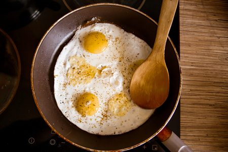 Cooking eggs in a frying pan at home on the stoveの写真素材