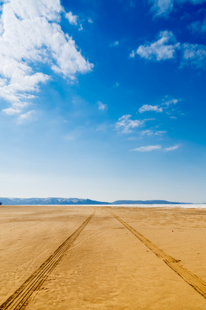 Car tracks in the sand on a blue sky backgroundの写真素材