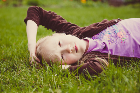Girl lying on green grass laughing and smilingの写真素材