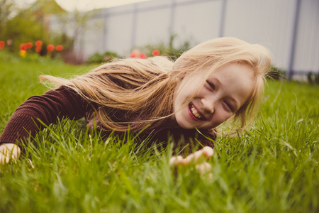 Girl lying on green grass laughing and smilingの写真素材