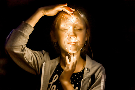 the girl holds the lights in the evening in the garden