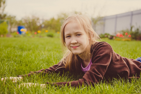 Girl lying on green grass laughing and smilingの写真素材