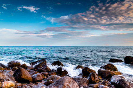 Sea surf at sunset - waves break against stonesの写真素材