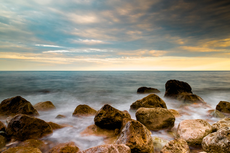 Sea surf at sunset - waves break against stonesの写真素材