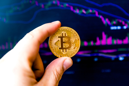 cryptocurrency in the hand against the background of the price chartの写真素材