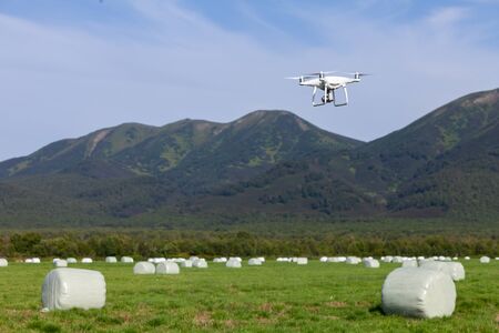 Russia, Kamchatka, 08/21/2019. Drone DJI Phantom 4 pro conducts photo and video shooting on agricultural fields where I harvest hay. Selective focus.のeditorial素材