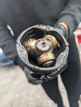 Greasy CV joint held by mechanic in black gloves after disassemblyの写真素材