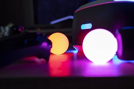 BRECHT,BELGIUM - 12 JUNE 2019: A Playstation VR headset, controller and move controllers lighting up the table in a dark living room. It is a nice colorful scene because of the different colors emitted by the different objects.のeditorial素材