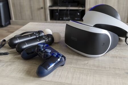 Brecht, Belgium - June 12 2019; A playstation 4 VR headset together with a playstation 4 controller and two move controllers on a table, ready to start gaming.のeditorial素材