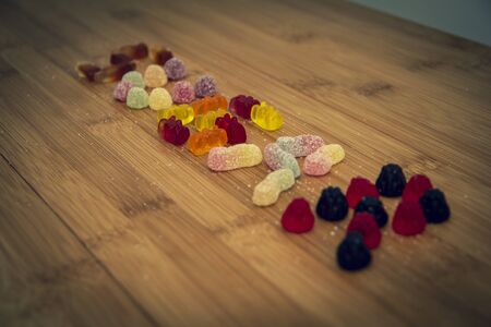 A lot of different kinds of colorful candy placed on a wooden plank so they spell the  word sugar. The sweets are sprinkled with some sugar.の写真素材