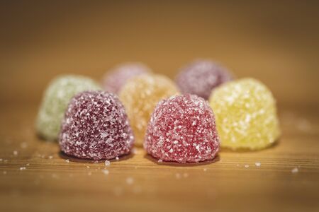 A close up portrait of soms colorful sugar sprinkled pieces of cany. The sweets are placed on a wooden table.の写真素材