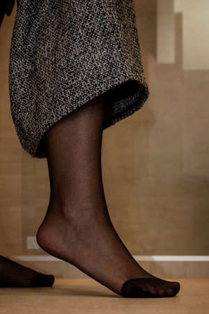 A close up portrait of a foot in sexy black pantyhose of a girl pulling up her skirt. The nylon is reinforced at the toes.の写真素材