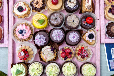 A top down portrait of a lot of colorful and delicious cupcakes in different flavors and forms. Some of the pastries have fruit on them.の写真素材