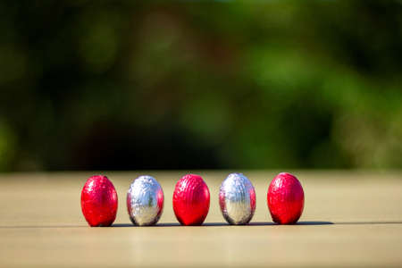 A portrait of chocolate easter eggs wrapped in tin colorful foiln standing up on a table ready to be found and eaten by children on their egg hunt.の写真素材