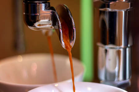A close up portrait of fresh hot coffee running out of the portafilter of a coffee machine.の写真素材