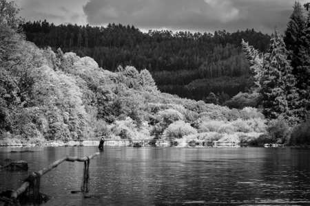 A portrait of a fly fisher in a river. The fisherman is reeling in his rod to try and catch some fish.の写真素材