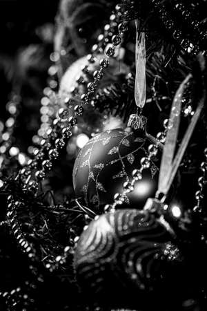 A black and white portrait of some christmas ornaments hanging on a christmas tree. There are balls, garlands and lights in the frame.の写真素材