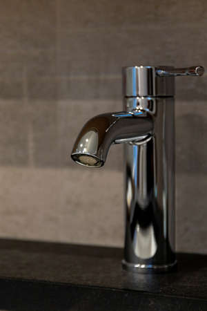 A portrait of a bathroom faucet with no water coming out of it. The handle is turned to the cold water side.の写真素材
