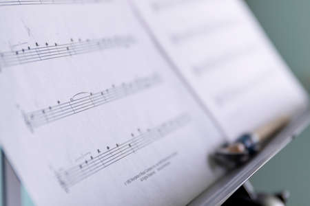 Brecht, Belgium - April 15 2020: A close up portrait of a music sheet with notes on it on a music stand. There is also a pencil on the stand to mark certain points on the notes of the music piece.の写真素材