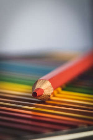 A colorful portrait of a pencil, which is of the color ed, lying on top of other different colored pencils in their box.の写真素材