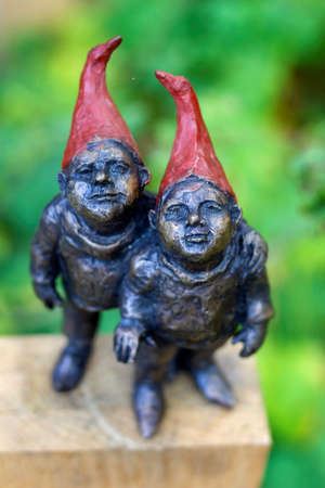 Beervelde, Belgium - October 13 2019: A top down portrait of two gnome statues made from metal. The steel gnomes are standing on a piece of wood and their hats are painted red.の写真素材