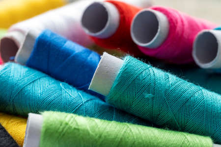 A portrait of multiple spools of thread lying on top of each other. Each roll of fiber has a different color. The yarn or wire is ready to be used in some needlework or sewing project.の写真素材