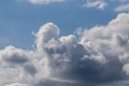 A portrait of a cloudy sky with a bit of blue sky at the top. The color of the clouds ranges from dark gray to white.の写真素材