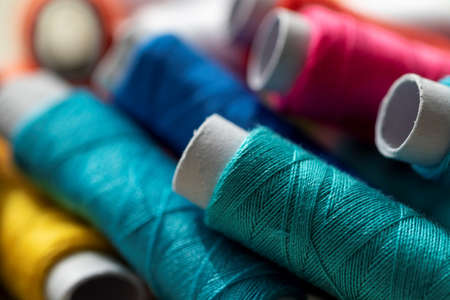 A portrait of multiple rolls or fiber lying on top of each other. Each spool of thread has another color. The yarn or wire is ready to be used of some kind of needlework like sewing or patching.の写真素材