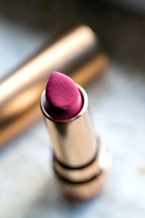 A portrait of a dark red lipstick with a gold shell. The make up item is not new and a bit used, but still in the same shape is it was sold.の写真素材