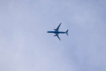 A portrait of a civilian airplane high up in the sky flying by. The belly of the airliner is...